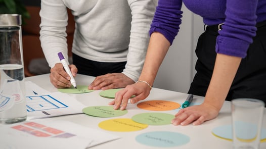 Marketing-Mitarbeiter, die an einem Schreibtisch stehen und Card Sorting durchführen