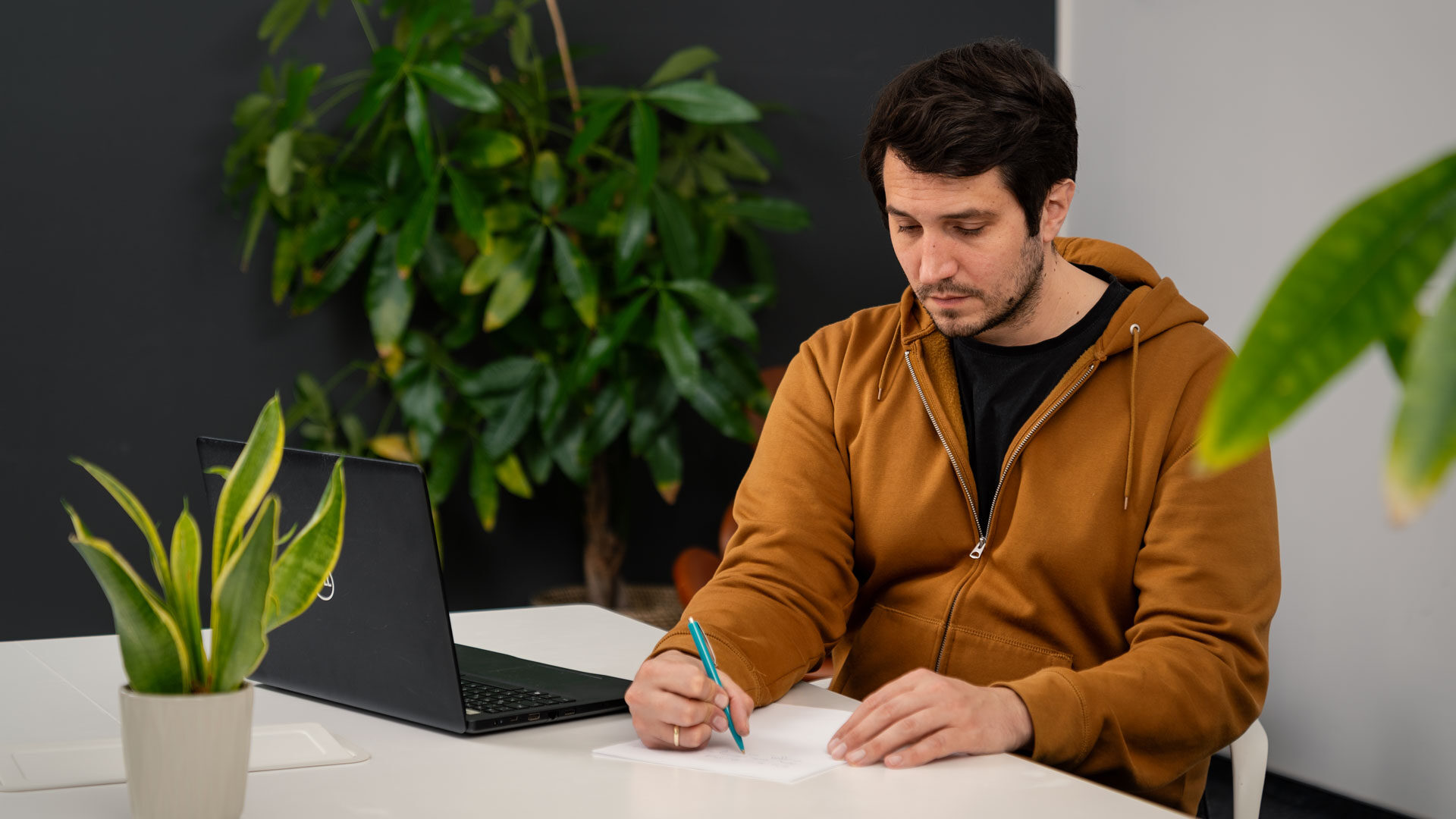 Marketing-Mitarbeiter, der an einem Schreibtisch sitzt und sich Notizen macht